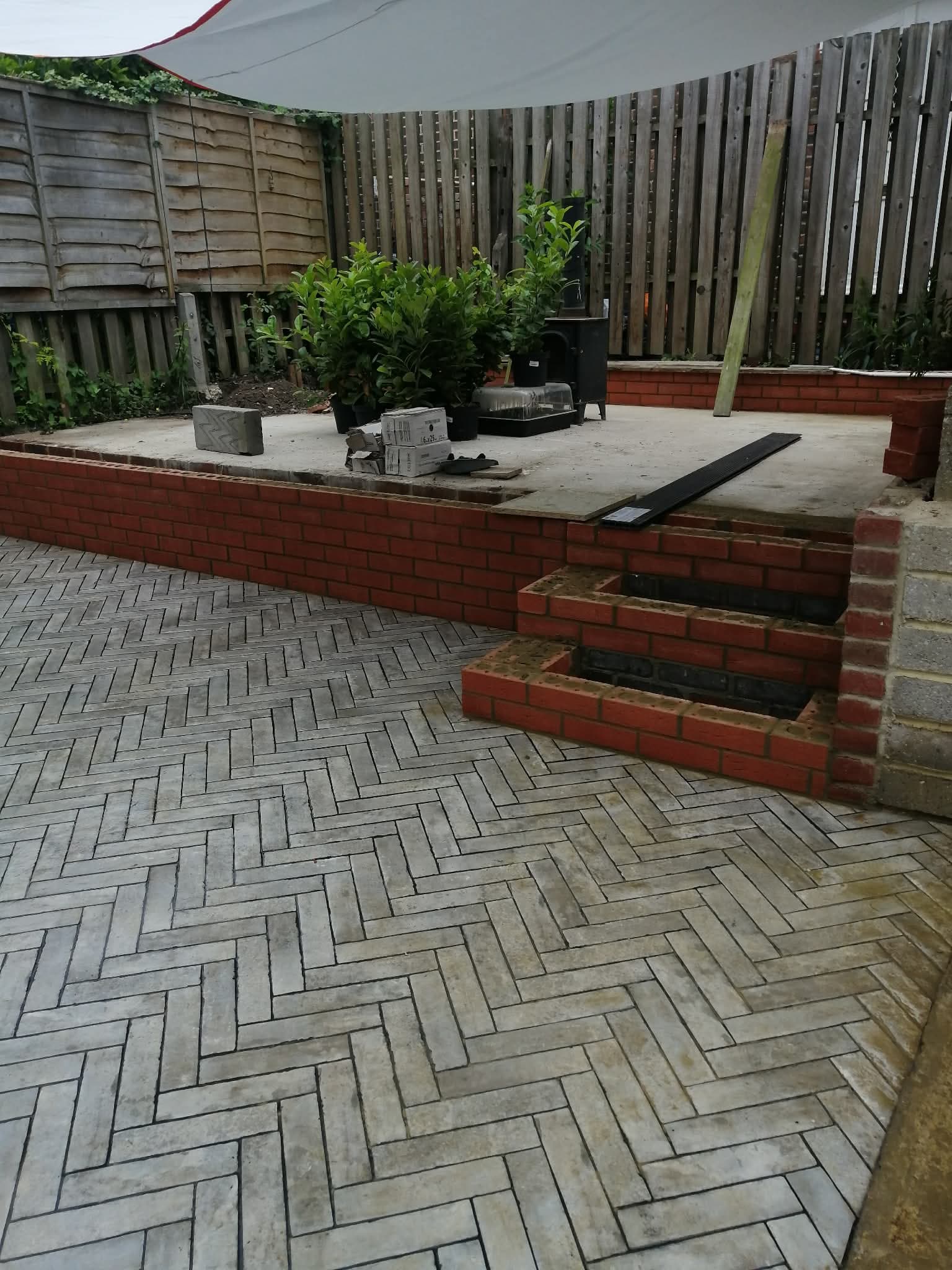 Raudonų plytų atraminė siena su laipteliais ir plytų grindimis