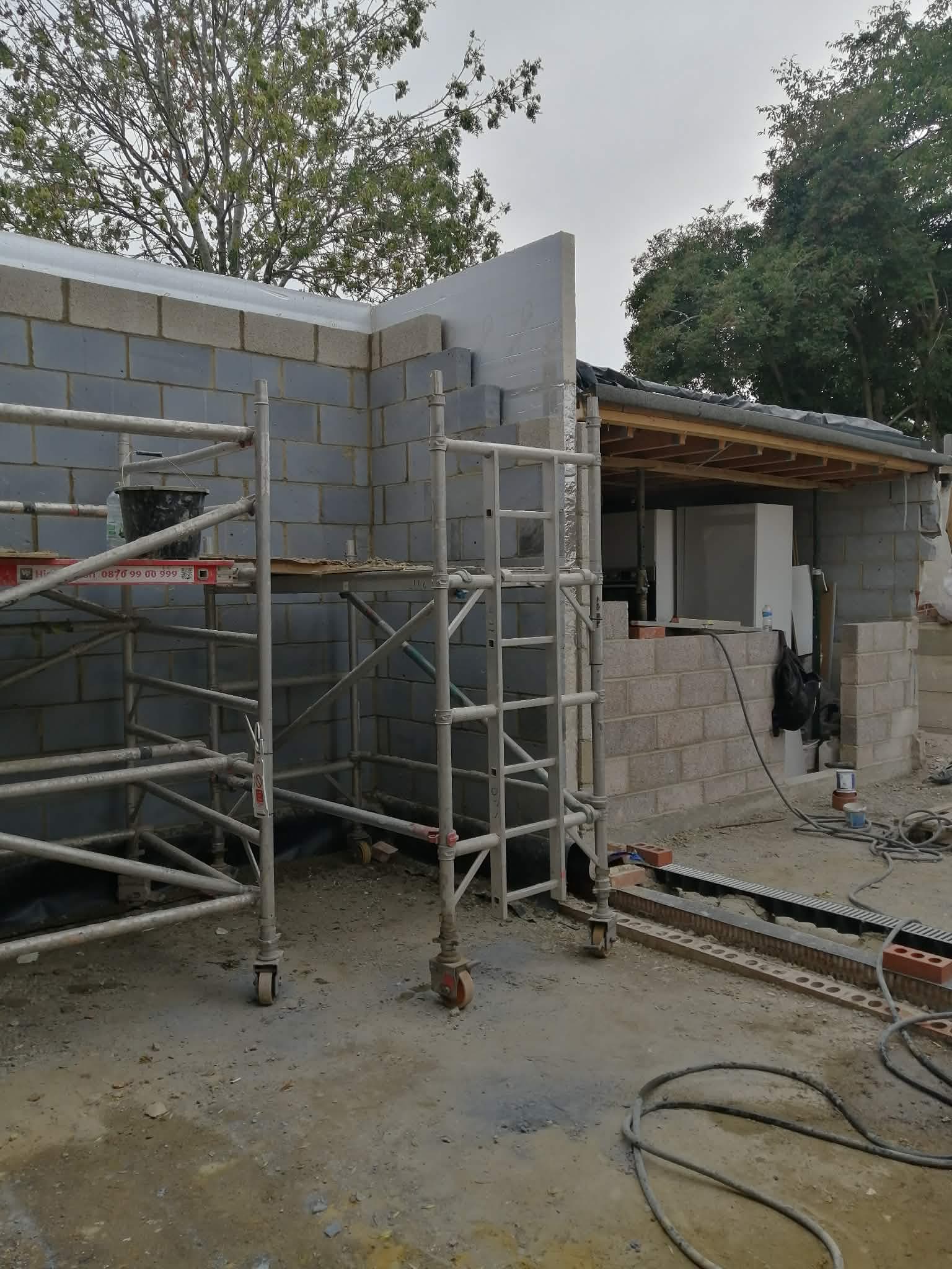 Pilkų betoninių blokelių sienos su pastoliais
