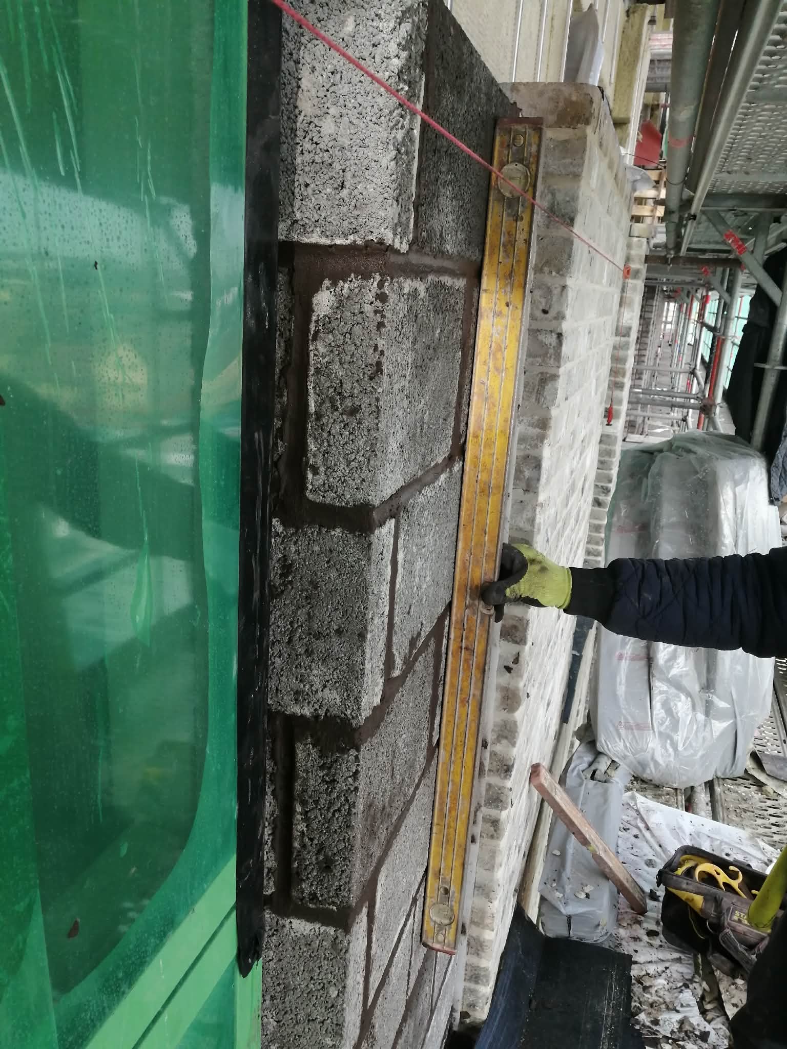 Statybininkas tikrina blokelių sieną su lygiu